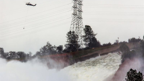 Un helicóptero sobrevuela la presa Oroville y el río Feather con sacos cargados de rocas para aliviar la emergencia ocasionada por la erosión del desagüe en la represa Oroville hoy, lunes 13 de febrero de 2017, en Oroville, California (EE.U