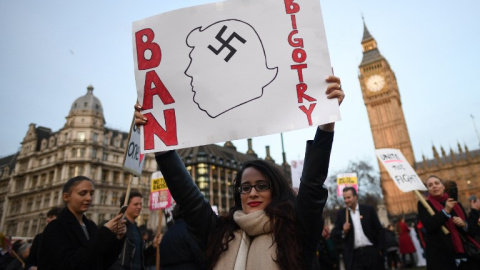 Una manifestante sujeta una pancarta en contra de las políticas antiinmigración de Trump. - AFP