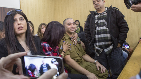 El soldado israelí Elor Azaría (c), es abrazado por su madre antes de escuchar el veredicto de un Tribunal militar israelí en Tel Aviv que le ha declarado culpable de la muerte de un palestino, al que remató de un tiro en la cabeza mientras