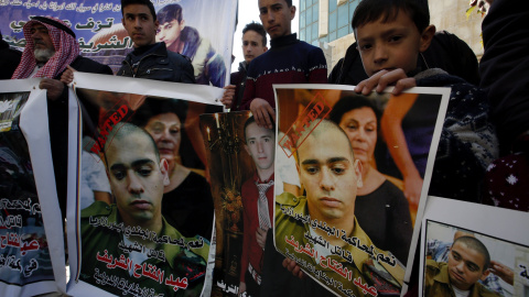 Palestinos sostienen pancartas con la imagen del soldado israelí Elor Azaría, durante una protesta en la ciudad cisjordana de Hebrón. EFE/ABED AL HASLHAMOUN