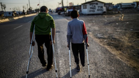 Dos niños sirios heridos pasean por un campamento de refugiados en Kilis, en el centro-sur de Turquía. - AFP