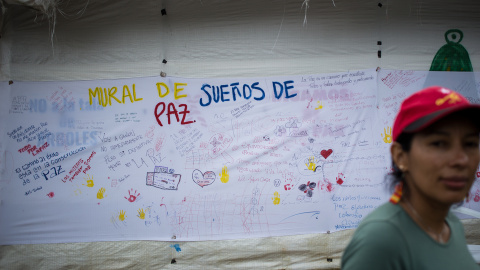 Una guerrillera de las FARC pasa delante de un mural en favor de los acuerdos de paz con el Gobierno colombiano, en la zona veredal de transición de La Elvira, en el Cauca.- JAIRO VARGAS