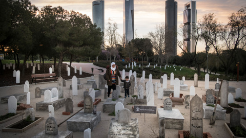 Una madre y su hijo observan el cementerio que Save the Children ha simulado en un parque de Madrid para recordar que, en Siria, han muerto 16.000 niños desde que comenzó la guerra, hace seis años. PEDRO ARMESTRE / SAVE THE CHILDREN