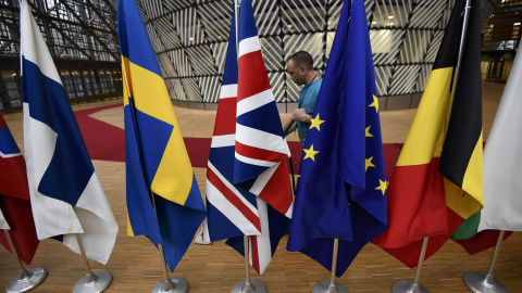 Un empleado limpia junto a las banderas europeas, dispuestas para la última cumbre de los lideres de la UE, en Bruselas, el pasado 9 de marzo. REUTERS/Dylan Martinez