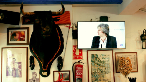 La primera ministra Británica retransmitida por la televisión de un bar junto a la imagen de un toro.REUTERS/Jon Nazca