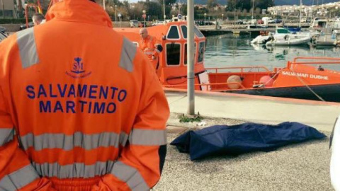 Un miembro de Salvamento Marítico junto al cuerpo rescatado de un inmigrante fallecido.- SALVAMENTO MARÍTIMO