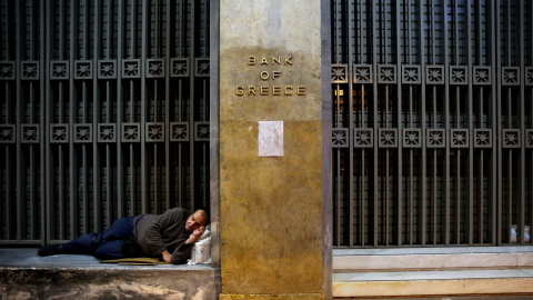 Un sintecho duerme a las puertas del Banco de Grecia en Atenas.REUTERS/Yannis Behrakis