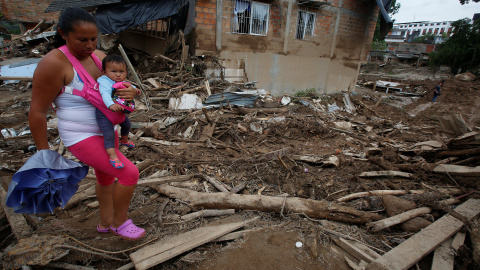 Una mujer con su niño camina entre los escombros de Mocoa. /REUTERS