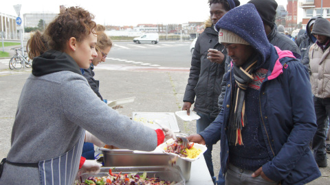 Varios refugiados esperan en la cola para recibir comida / ENRIC BONET