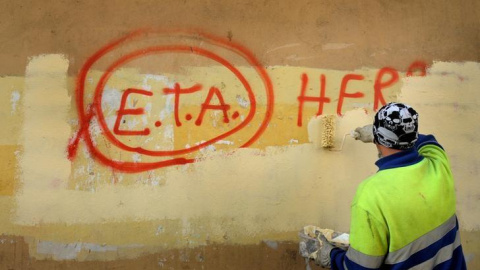 Un trabajador municipal borra un graffiti en el que se podía leer "ETA, la gente está contigo" en el pueblo vasco de Guernica, el día después que la banda terrorista anuncaria el cese de sus actividades en 2011.REUTERS/Vincent West