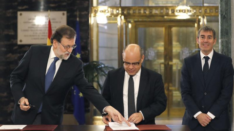 El presidente del Gobierno, Mariano Rajoy (i), durante firma con el secretario general de CC, José Miguel Barragán (c), del acuerdo suscrito entre sus dos partidos sobre los presupuestos generales del Estado de 2017, en un acto al que asist