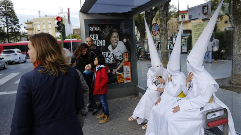 Unos nazarenos descansan en una parada de autobús en Sevilla. REUTERS/Marcelo del Pozo