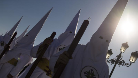 Nazarenos de la cofradía de San Gonzalo en el puente de Triana en esta calurosa tarde del lunes santo. EFE/Raúl Caro