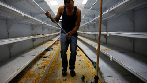 Un trabajador limpia las estanterías en un supermercado después de haber sido saqueado en Caracas. REUTERS / Carlos Garcia Rawlins