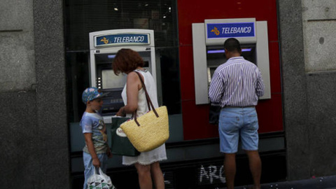 Un par de personas utilizan los cajeros de un banco en Madrid. EFE