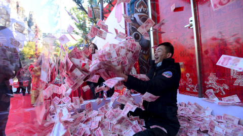 Un hombre intenta sacar billetes de 100 yuanes dentro de una jaula de cristal durante un evento realizado para celebrar el próximo Festival de Primavera, en un parque en Hangzhou, provincia de Zhejiang, China. REUTERS/Stringer