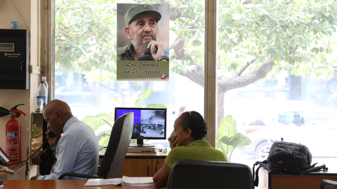 Trabajadores del centro internacional de prensa ante una fotografía de Fidel. /Marian León y Lucía M. Quiroga