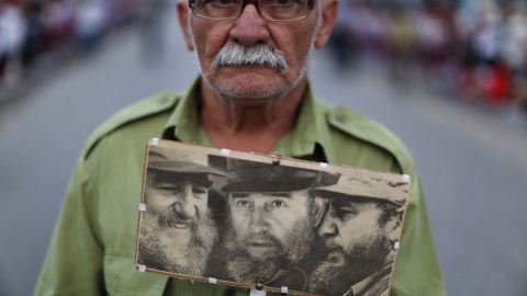 Un hombre sujeta fotografias de Fidel Castro mientras espera la caravana con las cenizas del exmandatario cubano. REUTERS