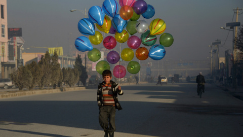 Un niño afgano camina mientras busca clientes que compren sus globos en las calles de Mazar -i- Sharif, el 3 de febrero de 2016. AFP PHOTO / Farshad Usyan