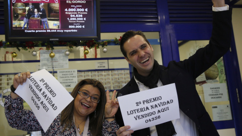 Marcos Delgado, dueño de la administración de lotería ubicada en la calle Condesa de Venadito en Madrid, acompañado de la vendedora Jenyffer Hoyos celebran su el segundo premio del Sorteo Extraordinario de la Lotería de Navidad que ha recaí