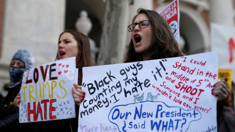 Dos chicas con pancartas contra Trump en la manifestación en Madrid / REUTERS