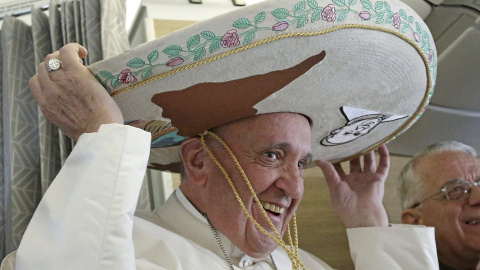 El Papa Francisco lleva un sombrero que recibió como regalo de un periodista mexicano, a bordo de un avión a La Habana. REUTERS/Alessandro Di Meo