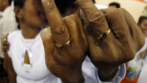 Una pareja de filipinos muestra sus anillos durante una boda masiva en Manila, Filipinas. EFE/FRANCIS R. MALASIG