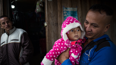 Un guerrillero sostiene en brazo a su hija de pocos meses en el campamento para desmovilizados de las FARC en La Fila, región de Tolima.-JAIRO VARGAS