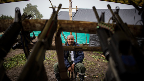 Un guerrillero de las FARC vigila las armas en la zona veredal de transición de La Fila, en Tolima. El proceso de desarme va más lento de lo acordado por los incumplimientos del Gobierno en varios puntos de los acuerdos con la guerrilla.- J