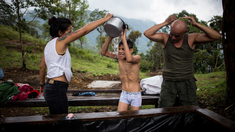 Una pareja de guerrilleros aseándose, junto al hijo de uno de ellos, en el campamento de desmovilizados de las FARC en La Fila, Tolima. El Gobierno no ha construido las infraestructuras básicas de habitabilidad que prometió en los acuerdo d