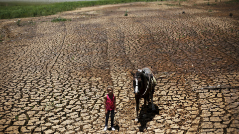 Una niña posa con su caballo en la tierra agrietada por la sequía en la presa Atibainha, en Cantareira, Nazare Paulista, cerca de Sao Paulo, Brasil. REUTERS / Nacho Doce