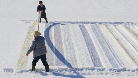 Una pareja coloca tela de kimonos sobre la nieve para su limpieza en Shiozawa en la prefectura de Niigata en Japón. EFE/Everett Kennedy Brown