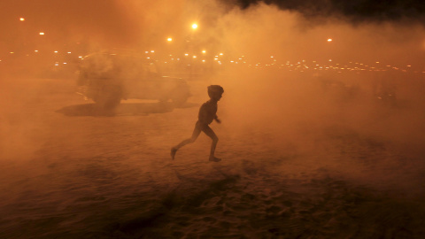 Un niño corre entre el humo procedente tras una fumigación en las orillas del río Ganges, en Allahabad, India. REUTERS/Jitendra Prakash