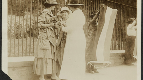 Una mujer policía detiene a las feministas Florencia Youmans (i) y Annie Arniel (d), por negarse a retirar su pancarta reclamando el voto femenino delante de la Casa Blanca, enWashington, en junio de 1917, en una de las fotografías que se c