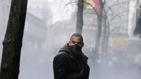 Uno de los manifestantes rodeado de los gases lacrimógenos lanzados por los policías belgas. EFE/OLIVIER HOSLET