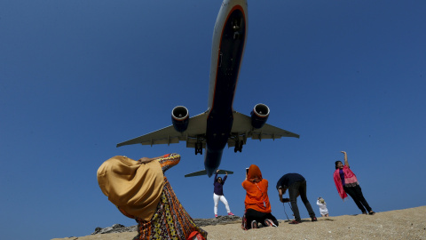 Unos turistas sacan fotos mientras un avión 'se pasea' por la Playa de Mai Khao Beach, en el Aeropuerto Internacional de Phuket, Tailandia. REUTERS/Athit Perawongmetha