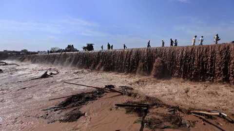 Varias personas cruzan una carretera inundada a las afueras de Peshawar en Pakistán. Las autoridades paquistaníes continúan con las tareas de rescate de 23 personas atrapadas en viviendas dañadas en la provincia de Khyber Pakhtunkhwa, en el