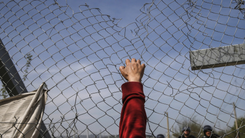 Un migrante intenta abrir una valla de la frontera en un campamento improvisado en la frontera entre Grecia y Macedonia, cerca de la localidad de Idomeni. REUTERS/Marko Djurica