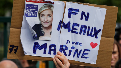 Un seguidor del Frente Nacional, sujeta una pancarta con la imagen de Marine Le Pen. REUTERS/Pascal Rossignol