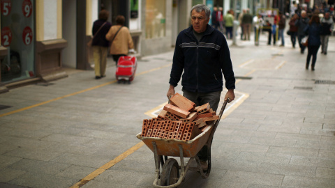 Un trabajador empuja una carretilla con ladrillos. REUTERS