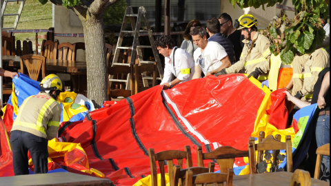 Varios operarios y bomberos retiran el castillo hinchable del restaurante Mas Oller, de Caldes de Malavella (Gerona), que ha volado unos 40 metros por encima del tejado del establecimiento, provocando la muerte de una niña, y causando herid