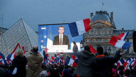 Los seguidores de Emmanuel Macron siguen en una pantalla gigante la primera intervención del presidente electo francés, en la explanada del Museo del Louvre, donde se celebra su victoria en las presidenciales. REUTERS/Jean-Paul Pelissier