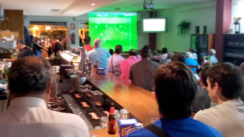 Clientes de un bar viendo un partido de fútbol por televisión.