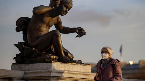 Una mujer con mascarilla protectora camina por el Puente Alexandre III este jueves en París.