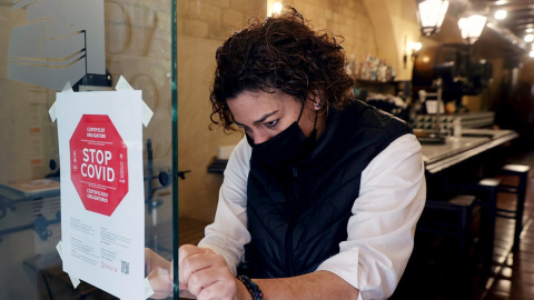 Una empleada de un hotel coloca un cartel a la entrada de su restaurante en València.