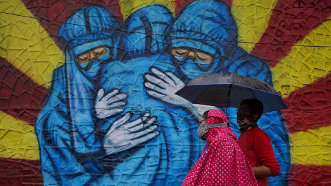 Una mujer y su hijo pasan frente a un graffiti en Mumbai, India.