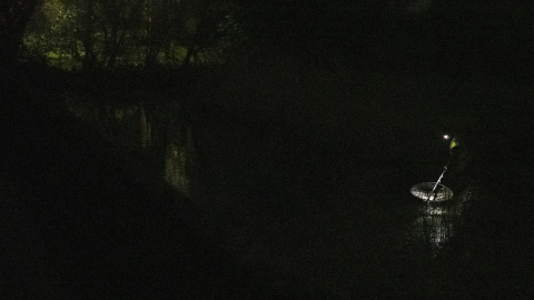 Una luz en mitad de la noche, un hombre que faena solo en la orilla