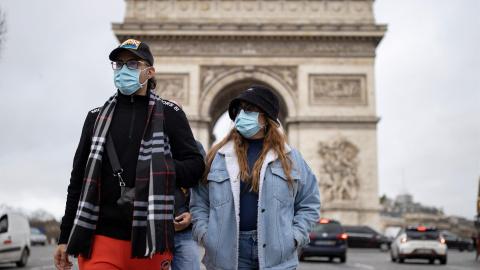 Los peatones con mascarillas caminan por los Campos Elíseos en el centro de París.