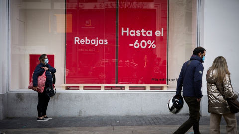 5/1/22-Varias personas pasan delante de un escaparate con cartel de rebajas en una calle comercial del centro de Madrid, a 2 de enero de 2022, en Madrid, (España).