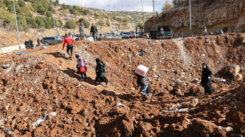 Personas que huyen de los bombardeos israelíes en Líbano cruzan un cráter, causado por un ataque israelí, en el área de Masnaa, en el lado libanés del cruce fronterizo con Siria, el 20 de noviembre de 2024